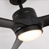 A close-up of a matte black modern ceiling fan with three blades and an integrated round light, shown against a plain light gray background.