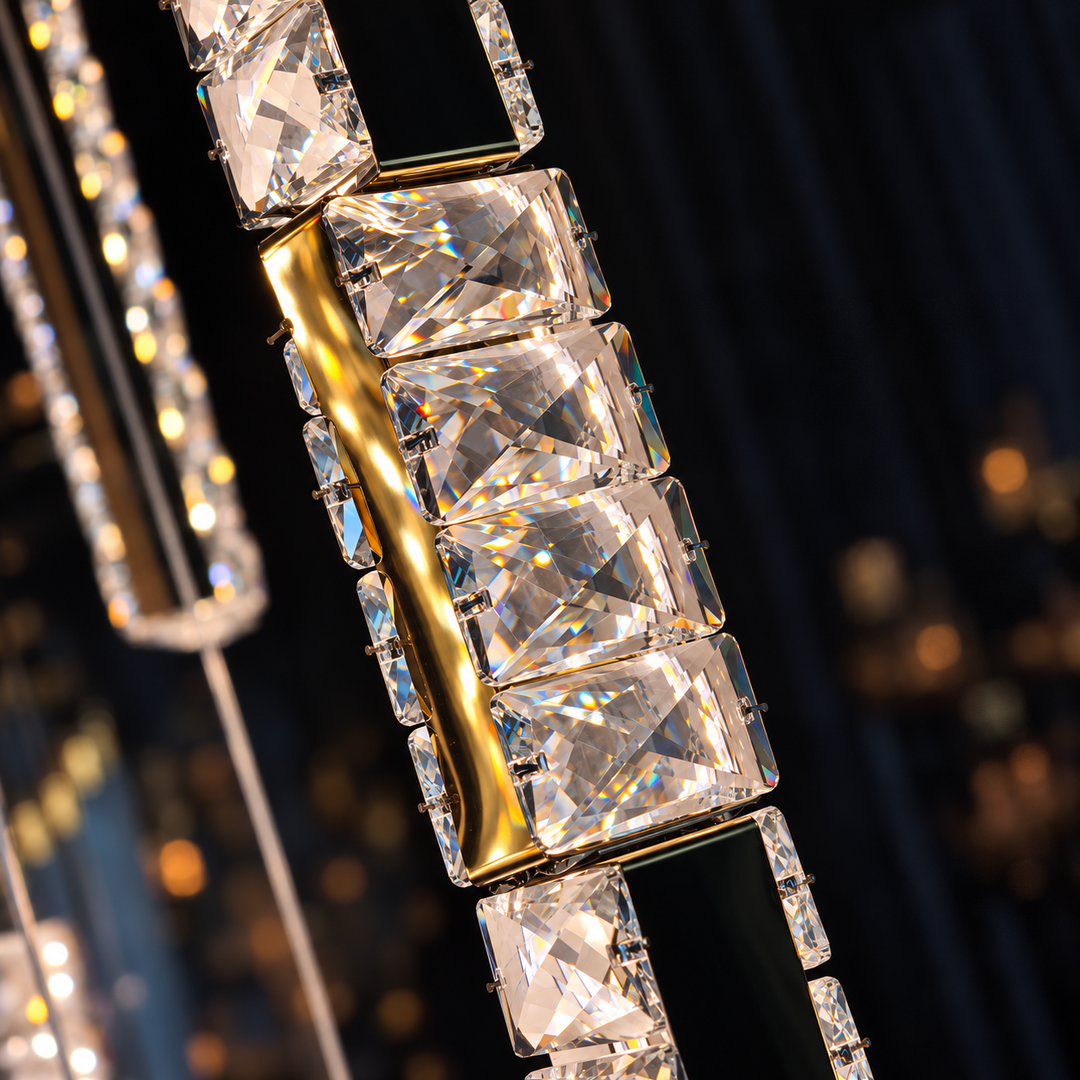 Close-up detail of a luxury crystal chandelier featuring rectangular clear glass prisms set in polished gold and black metal frames, with sparkling reflections against a dark, softly blurred background.
