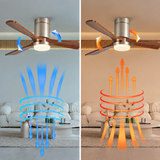 Wood-bladed ceiling fan light with silver housing above a living room sofa, shown beside blue downward and orange upward airflow arrows.