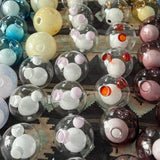 Chandelier glass globes with clear and tinted outer shells, rounded inner forms and circular openings sit on a patterned rug.