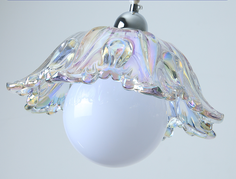 Pendant light close-up showing an iridescent scalloped glass shade above a white globe, with a silver fitting against a pale background.