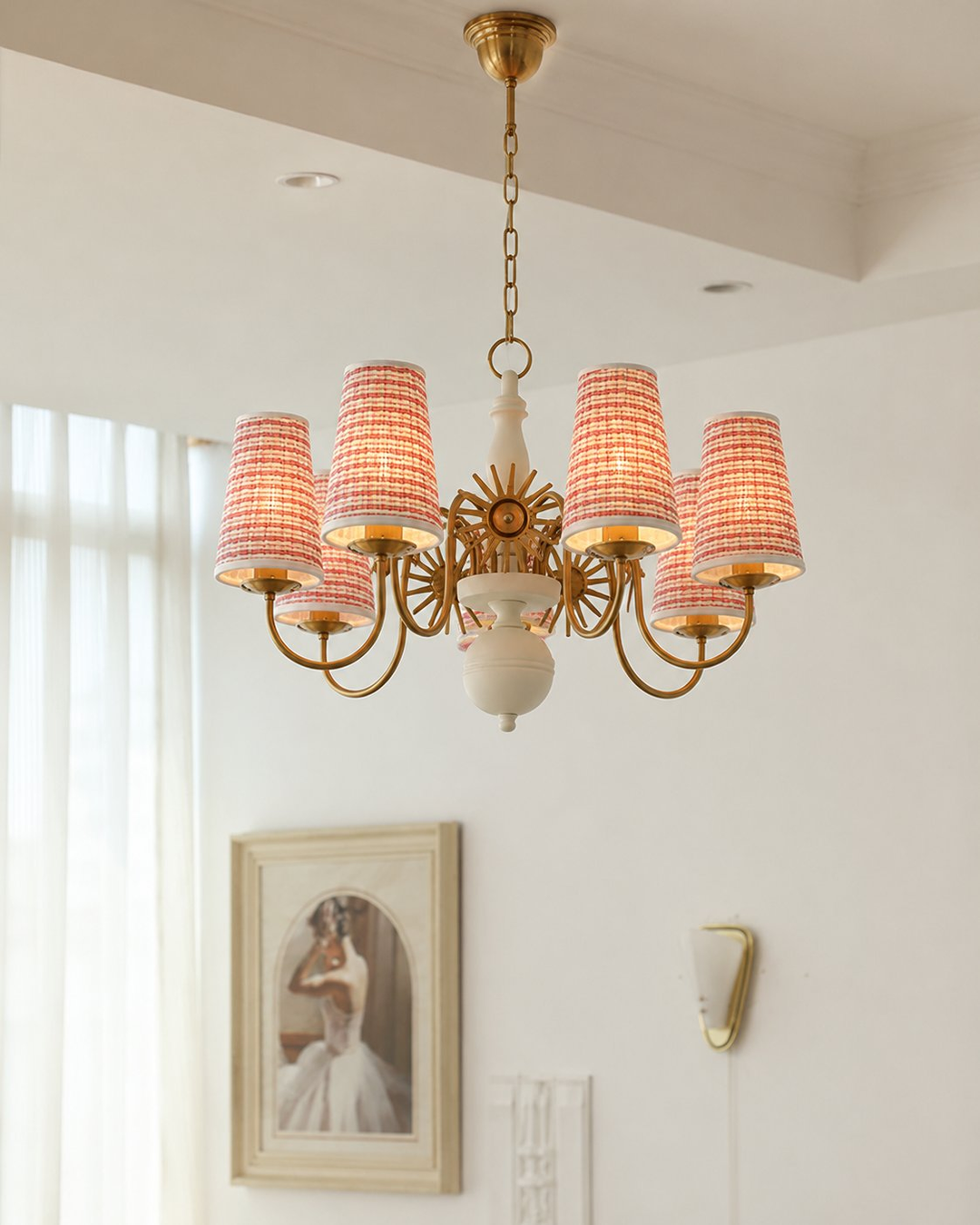 Chandelier with red lampshades in a room with a window and wall art.
