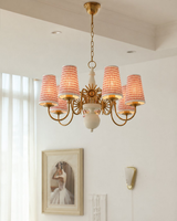 Chandelier with red lampshades in a room with a window and wall art.
