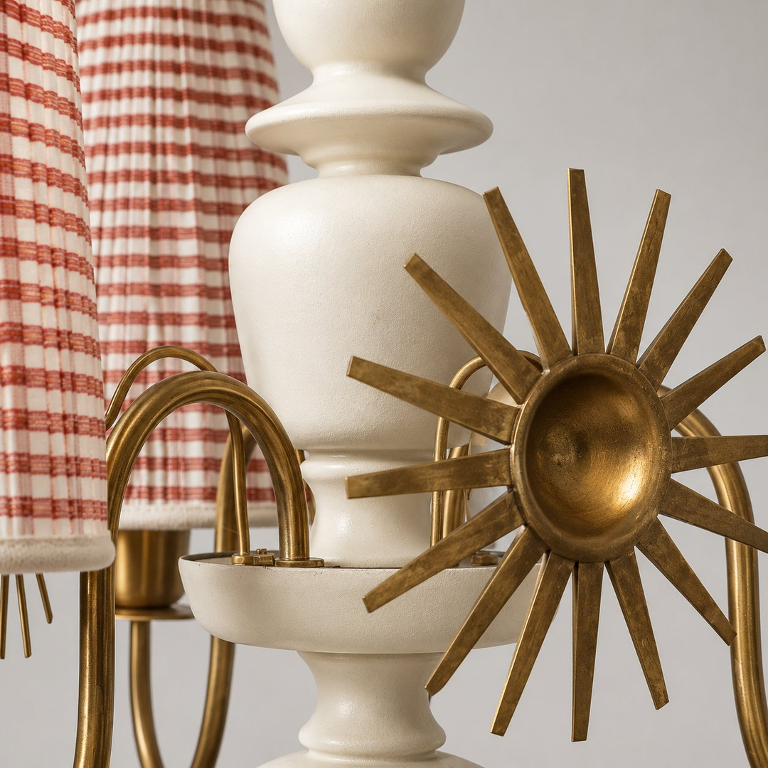 Chandelier close-up showing a cream central column, antique brass-tone curved arms and sunburst ornament, with red-and-cream striped fabric shades.