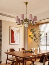Dining room with a wooden table, chairs, and a chandelier with red and white striped lampshades.