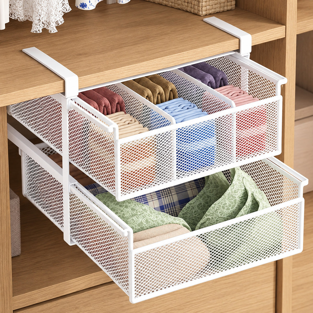 Two white metal mesh drawer organizers hanging from a wooden shelf, filled with folded clothing in assorted colors.