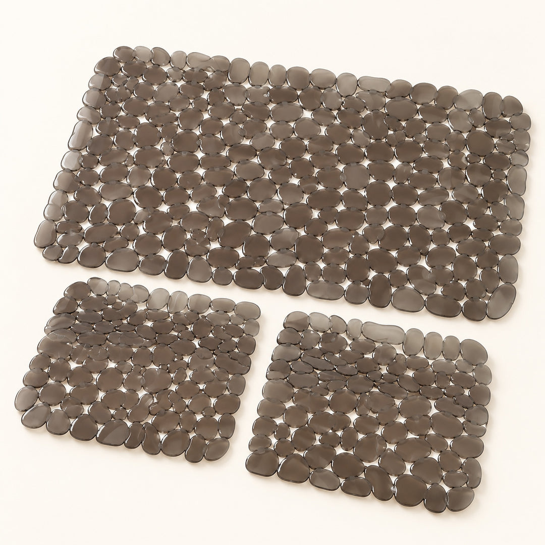 Three pebble mat floor mats in different sizes, made of smooth gray stone-like pieces, arranged on a plain white background.