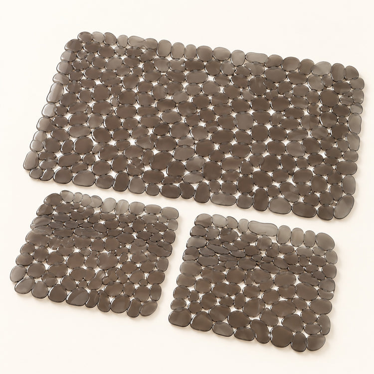 Three pebble mat floor mats in different sizes, made of smooth gray stone-like pieces, arranged on a plain white background.