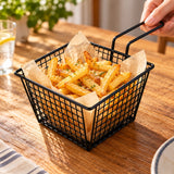 Black wire serving basket with golden fries on a dining table.