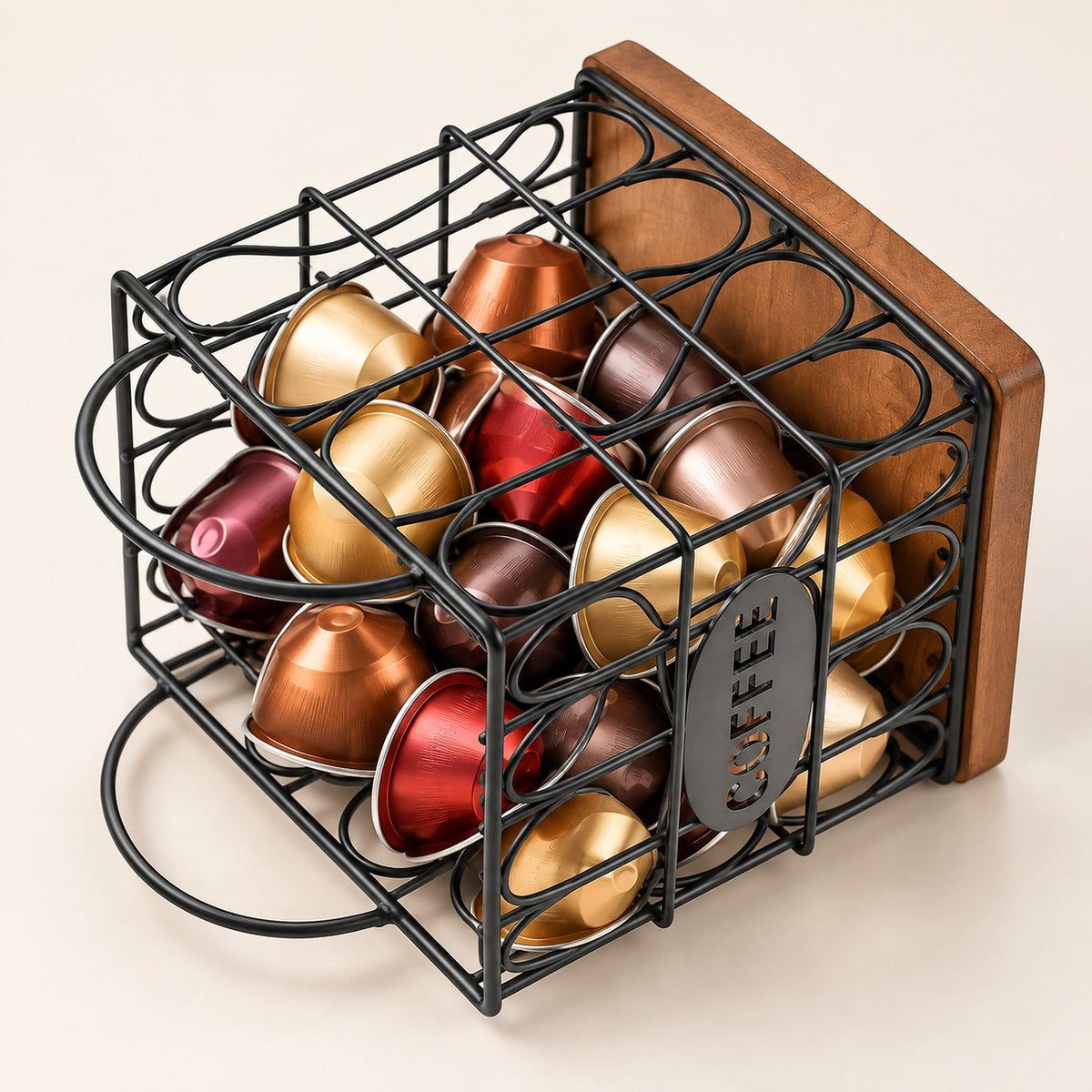 A black metal wire coffee capsule organizer with a wooden back panel, filled with assorted coffee capsules in gold, bronze, red, and brown tones, on a light beige background.