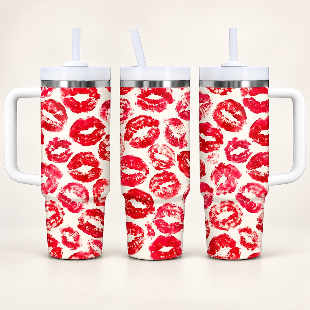 Three handled tumbler cups with white lids and straws, decorated with a repeating red lipstick kiss-print pattern on a white background, shown against a light beige studio backdrop.