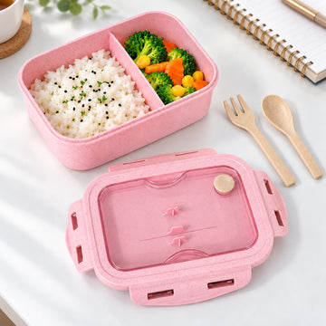 Two-compartment pink lunch box with packed lunch, fork and spoon.