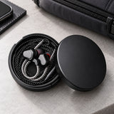 Wired earbuds neatly stored inside the lined round case; earphones not included.