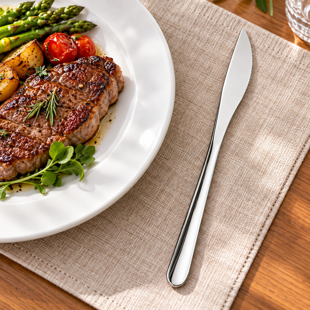 Silver dinner knife beside a steak plate; food and plate not included.