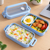 Blue two-layer bento lunchbox with rice and vegetables for an office lunch.