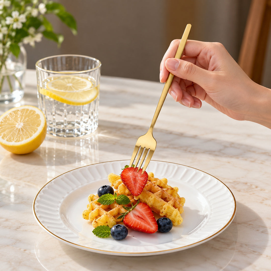 Gold dinner fork used to pick up a piece of fruit at the table.