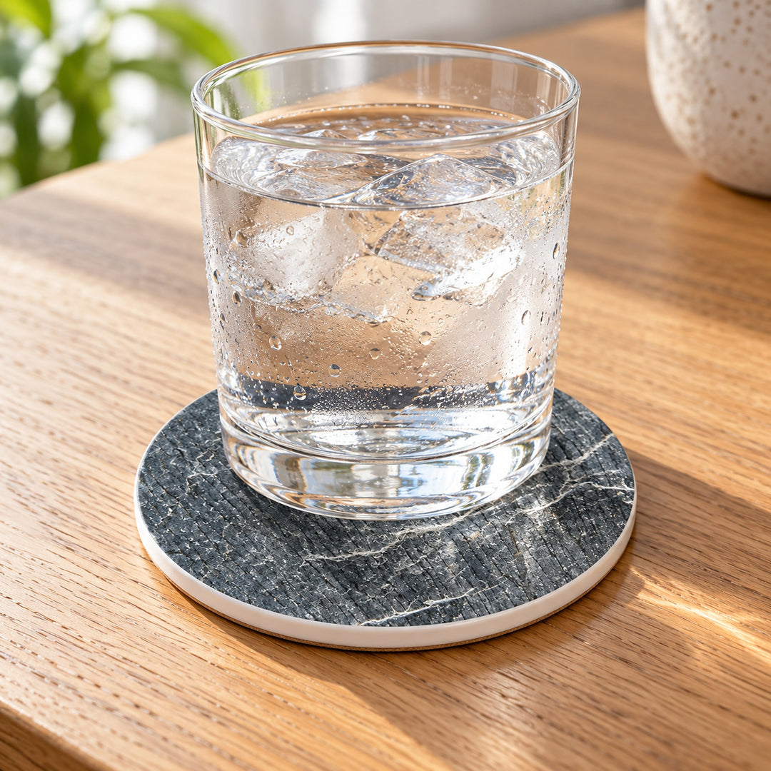 One charcoal ceramic coaster under a cold glass; drinkware not included.
