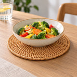 Round rattan trivet supporting a serving bowl on a dining table.
