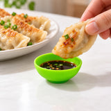 Lime-green mini silicone bowl holding dip beside dumplings.