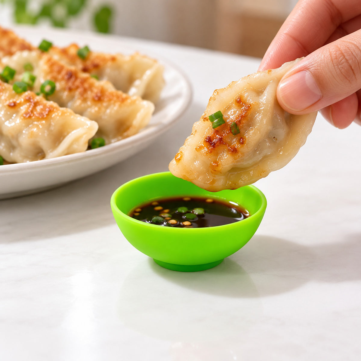 Lime-green mini silicone bowl holding dip beside dumplings.