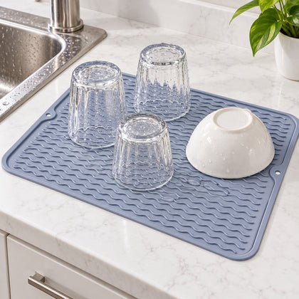 Gray silicone mat drying glasses and a bowl beside a sink.