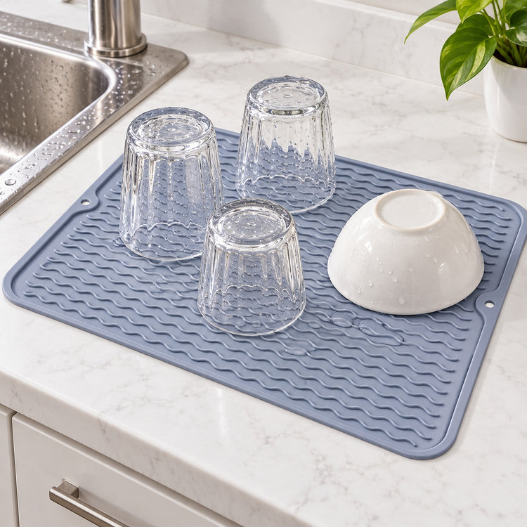 Gray silicone mat drying glasses and a bowl beside a sink.