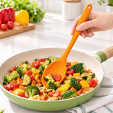 Orange medium silicone spoon stirring vegetables in a pan.