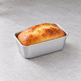 Mini aluminum loaf pan holding a small homemade bread loaf.