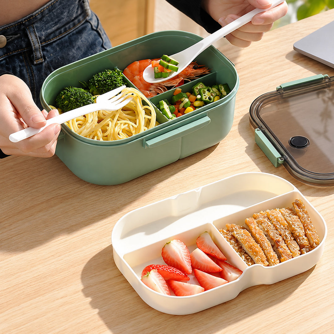 Green lunch box with separated meal and fruit for work.