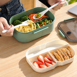 Green lunch box with separated meal and fruit for work.