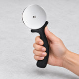 Hand gripping the curved black pizza cutter handle behind its finger guard.