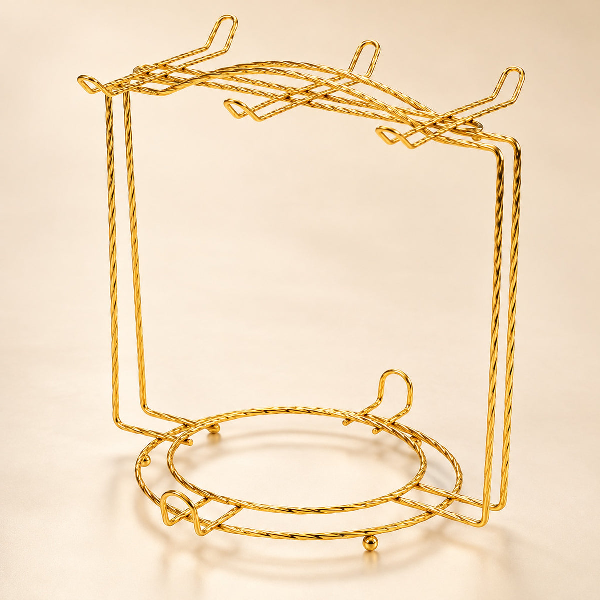One empty gold twisted-wire cup-and-saucer rack with upper cup hooks and lower plate ring.