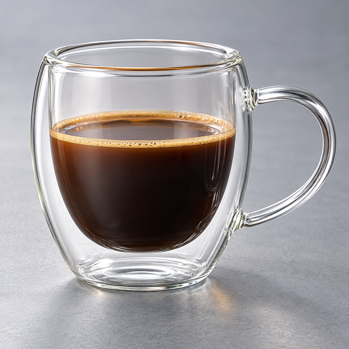 Close view of the inner and outer glass walls around coffee in a clear handled mug.