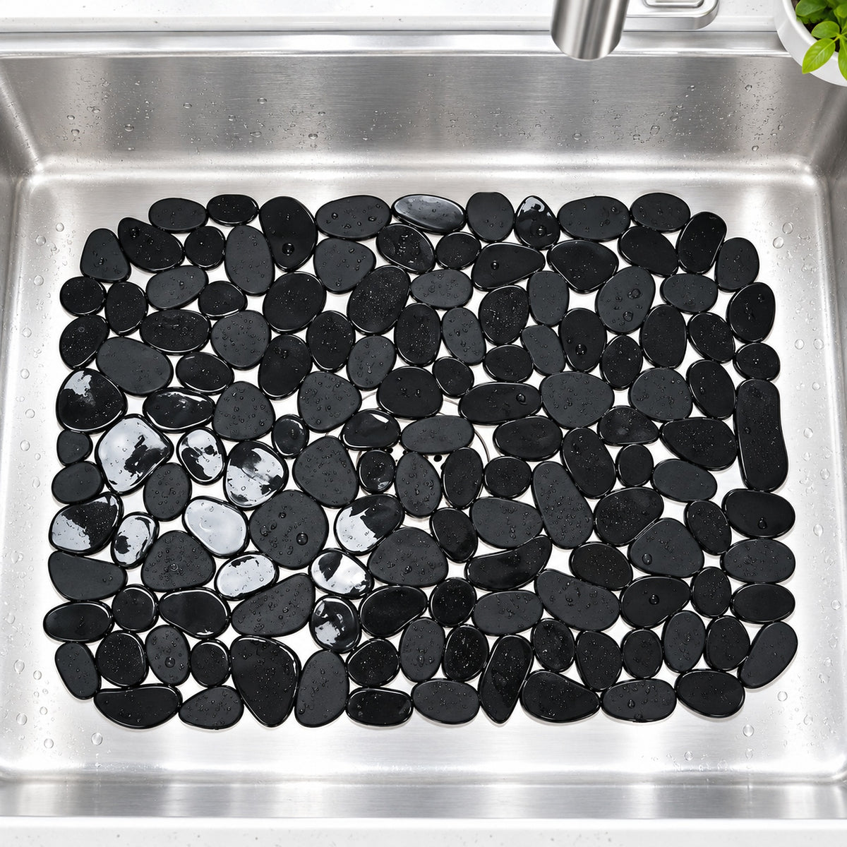 Black pebble-look wall tiles arranged in a rectangular pattern inside a stainless steel kitchen sink.