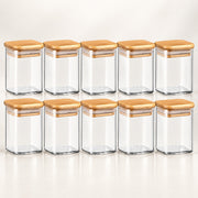 Ten clear glass spice jars with light brown bamboo lids, arranged in two rows of five on a clean white background.