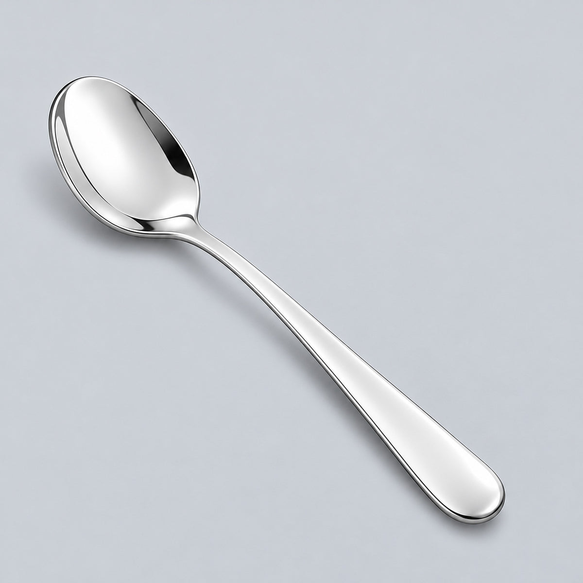 Silver teaspoon showing its shallow oval bowl and rounded metal handle.