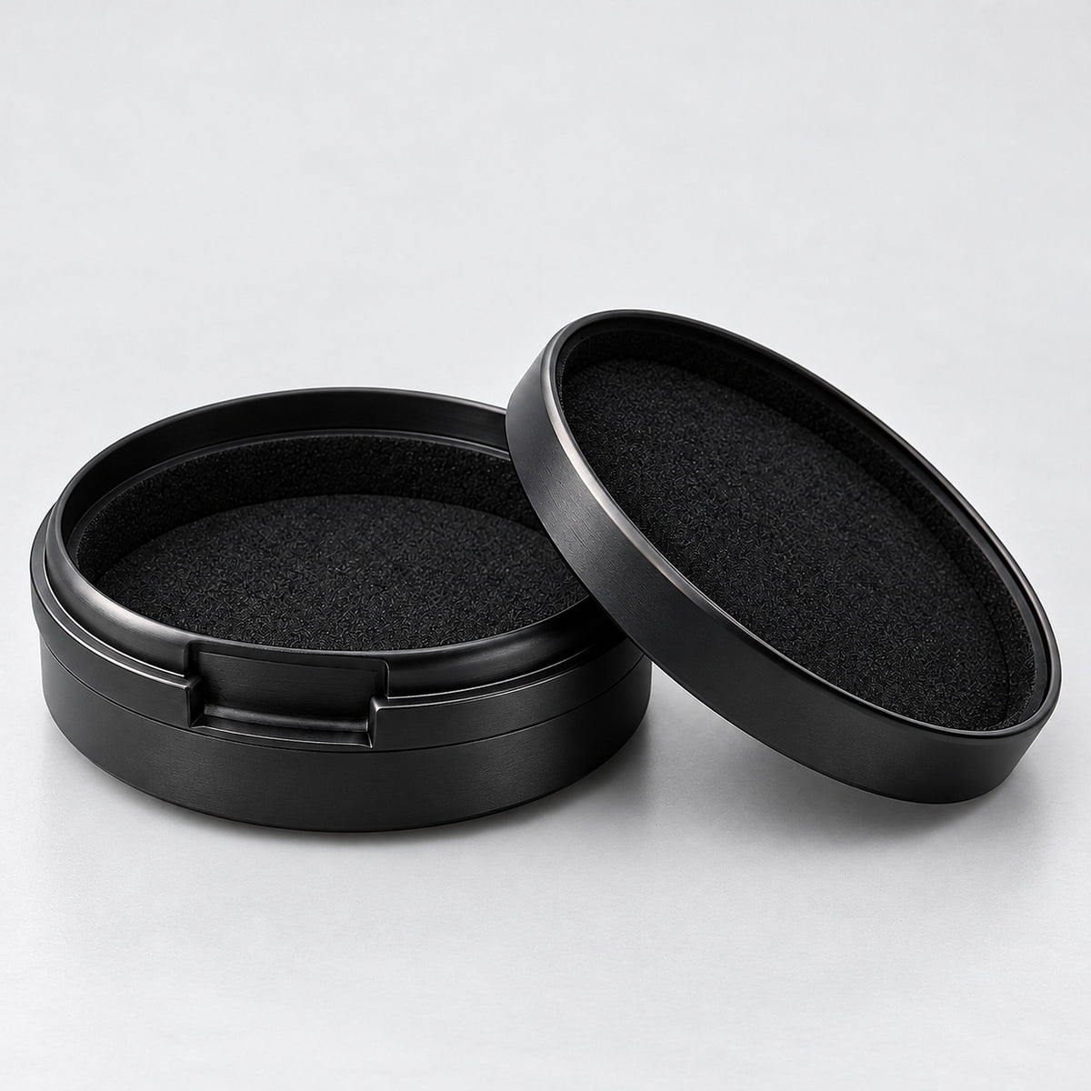 Open round aluminum case showing its soft black interior lining.