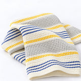 Yellow striped 100% cotton towel showing raised waffle texture and stitched hem.