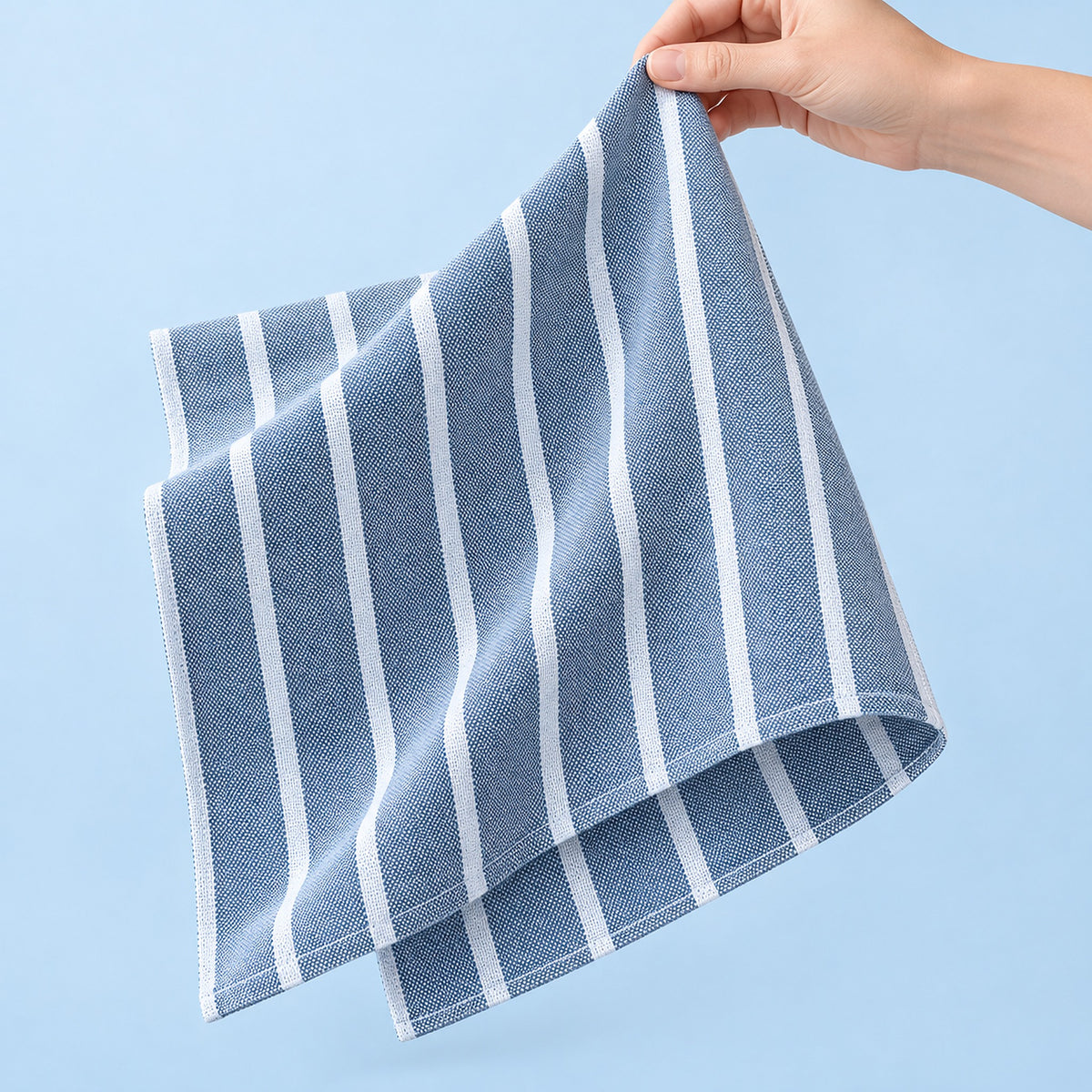 Soft folds and stitched hem of the thin blue-striped cotton towel.