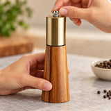 The pepper grinder top adjustment knob being turned by hand.