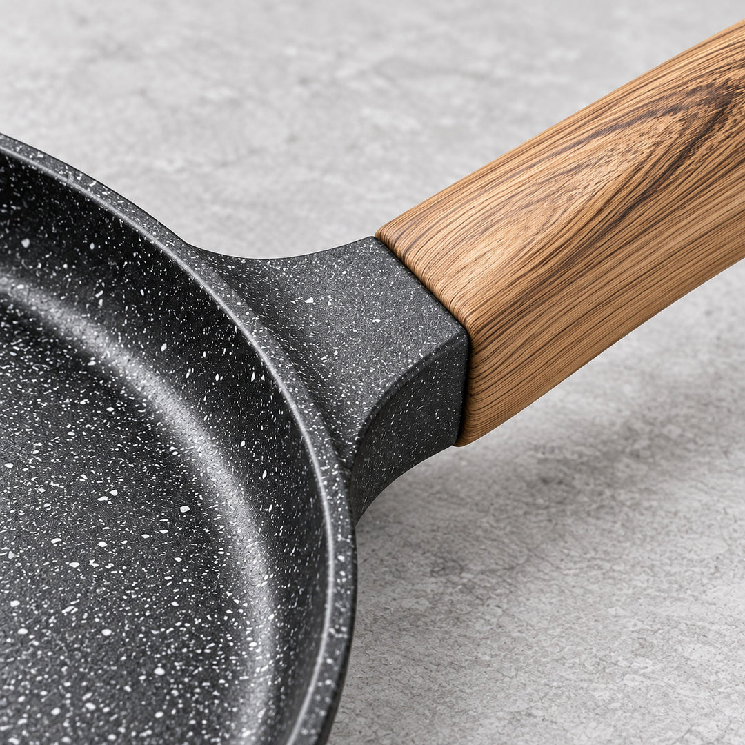 Speckled cooking surface and wood-grain bakelite handle connection.