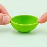 Fingertips gently flexing the rim of a small silicone bowl.
