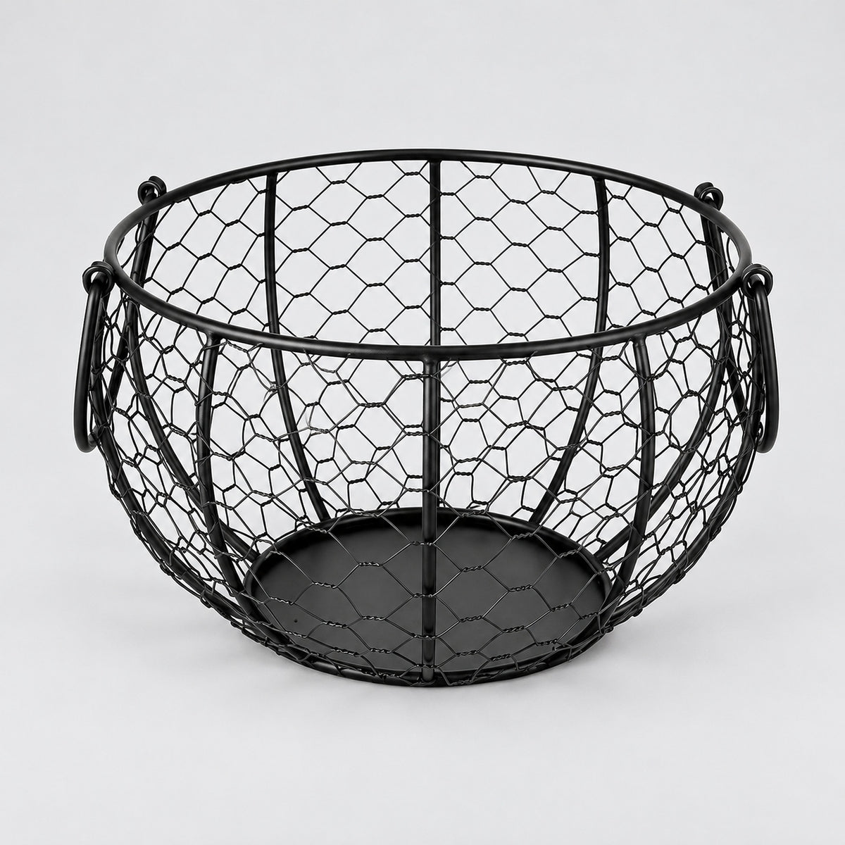 One empty black iron egg basket with two folding handles and a solid circular base.