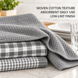 Three folded gray kitchen towels with woven cotton textures, including a plaid pattern, displayed on a marble countertop with a glass and plates in the background. Text on the image reads: 'WOVEN COTTON TEXTURE ABSORBENT DAILY USE LOW-LINT FINISH'.