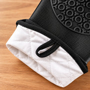 Close-up of a black and white quilted fabric pouch or sleeve with a black elastic band and a black textured circular patch, shown on a wooden surface.
