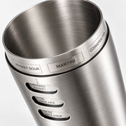 Close-up of a brushed stainless steel cocktail muddler with engraved flavor and ratio labels including Whiskey Sour, Martini, Cosmopolitan, Blended Whiskey, 1 oz Lemon Juice, and 1/2 oz Campile Syrup.