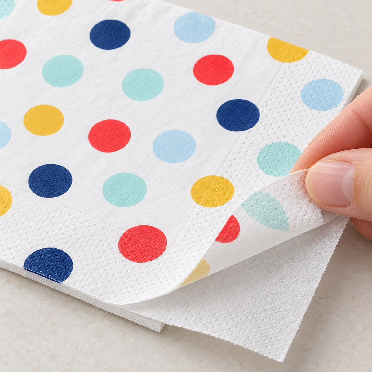 Two thin tissue plies at the corner of a printed paper napkin.