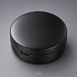 One closed black round storage case; case-only contents.