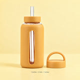 Included yellow glass bottle with silicone sleeve, two lids and one wide straw.