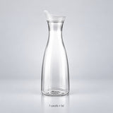 One empty clear plastic carafe with its fitted lid.